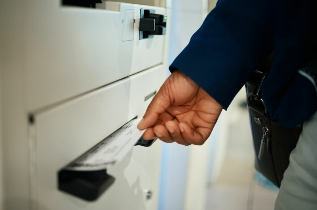 Dłoń w ciemnym rękawie wyjmująca papier z szuflady szafy biurowej